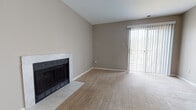 This single-floor residence offers a well-organized layout with a warm, neutral color palette throughout. The living room serves as the heart of the home, highlighted by a marble-surround fireplace and a large sliding glass door fitted with vertical blinds that floods the space with natural light and provides access to the outdoors. Plush carpeting runs through the living and bedroom areas, contributing to a comfortable, inviting atmosphere.

The galley-style kitchen is thoughtfully designed with warm oak cabinetry, dark granite-look countertops, a mosaic tile backsplash, and a full suite of black appliances including a refrigerator, dishwasher, and gas range. A bi-fold pantry door provides convenient additional storage. Hardwood flooring in the kitchen and entry areas creates a clean transition between spaces.

The bedrooms are generously sized, carpeted, and filled with natural light from well-placed windows. Each includes closet storage, with at least one bedroom featuring a walk-in style closet. Two full bathrooms serve the residence, each outfitted with warm oak vanities, white countertops, a tub-shower combination, and hardwood flooring, lending a consistent and tidy aesthetic. A hallway connects the private areas of the home, completing this functional and comfortable single-level layout.
