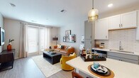 Located at 110 N Chestnut St in Olathe, Kansas, this single-floor residence offers a thoughtfully designed open-concept layout that seamlessly connects the living, dining, and kitchen areas. Light wood-style flooring runs throughout the main living space, contributing to a clean, contemporary aesthetic.

The kitchen is outfitted with stainless steel appliances, white upper shaker cabinets, gray lower cabinets with matte black hardware, a classic white subway tile backsplash, and a central island with pendant lighting overhead—providing both additional prep space and casual seating. The living area benefits from natural light streaming through French doors that open to an exterior access point, accompanied by sheer floor-length curtains.

Two bedrooms feature plush carpeting, generous windows with blinds, and ample room for furnishings. The primary bathroom is notably spacious, offering a dual-sink vanity with gray cabinetry, a soaking tub, a tiled shower, and a doorway leading directly into a walk-in closet. Neutral tones and consistent modern finishes are carried throughout, creating a cohesive and inviting atmosphere across the entire unit.