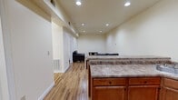 Located at 1024 Philadelphia St in Indiana, PA, this 2-bedroom, 1-bathroom home offers a functional and well-appointed single-floor layout. The open-concept kitchen and living area forms the heart of the space, with warm hardwood-style flooring running throughout. The kitchen is equipped with black appliances, including a range, over-the-range microwave, and refrigerator, complemented by warm-toned wood cabinetry and granite-style countertops that extend to a kitchen island. A stainless steel sink and ample upper and lower cabinet storage add practicality. The adjoining living area is bright and open, illuminated by recessed ceiling lighting, creating a welcoming atmosphere. Both bedrooms feature the same hardwood-style flooring, natural light from windows with blinds, and closet storage — the primary bedroom includes a dedicated closet with a rod and shelving. The full bathroom is fitted with a single-vanity featuring a white countertop and wood cabinetry, a large mirror with overhead lighting, a towel bar, and a soaking tub with shower. A connecting hallway ties the rooms together efficiently. Neutral wall tones and clean finishes throughout lend the home a fresh, move-in ready feel.