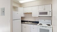 Located at 1352 Canyon Rd in Ogden, Utah, this one-bedroom, one-bathroom residence offers a practical and well-organized single-floor layout. The open living area features a combination of wood-look vinyl flooring and plush carpet, with a large window that invites natural light and provides views of the surrounding greenery. The kitchen is efficiently designed with white cabinetry, dark speckled countertops, a full-size refrigerator, an electric range, a built-in microwave, and a stainless steel sink — offering everything needed for everyday cooking. The bedroom is a comfortably sized, carpeted retreat featuring a wall-mounted air conditioning unit, a window with natural light, and a sliding-door closet providing ample storage. The bathroom is clean and modern, appointed with a white vanity offering generous cabinet and drawer storage, a well-lit mirror, and a full bathtub. Throughout the unit, neutral tones, white trim, and textured ceilings create a cohesive, understated aesthetic. The space is practical and move-in ready, making it a solid option for those seeking straightforward, functional living in the Ogden area.