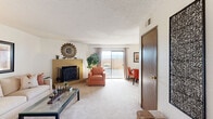 Located in Albuquerque, NM, this single-floor, 2-bedroom, 2-bathroom residence offers a functional and comfortable layout across a well-utilized footprint. The living room serves as the heart of the home, featuring a distinctive brick fireplace, soft carpeting, and a sliding glass door that opens to a private patio, allowing natural light and outdoor views to fill the space. The adjacent dining area connects seamlessly to the kitchen, which is equipped with warm honey-toned wood cabinetry, white appliances including a range, refrigerator, and dishwasher, light countertops, and hardwood-style flooring. A breakfast bar adds convenience to the open flow between the kitchen and dining space.

The spacious primary bedroom accommodates generous furniture and includes a sliding-door closet, soft carpet, and a textured ceiling. The second bedroom is similarly comfortable. Both bathrooms are clean and practical — one features a tub-shower combination with glass sliding doors, while the other offers a standalone shower enclosure alongside warm wood cabinetry and hardwood-style flooring. Two hallways provide efficient circulation throughout the home. Overall, the residence presents a cohesive, livable design with warm tones and practical finishes throughout.