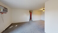 Located at 3120 Staten Ave in Lansing, Michigan, this single-floor, 2-bedroom, 1-bathroom unit offers a practical and functional layout. The combined living room and kitchen area serves as the heart of the space, with the living room featuring gray wall-to-wall carpeting, a wall-mounted air conditioning unit, baseboard heating, and a sliding glass door that opens to a private balcony, allowing natural light to filter in. A ceiling fan is present in the adjoining area near the kitchen entry.

The kitchen is designed with warm wood-toned cabinetry, a peninsula-style counter with a double stainless steel sink, a white electric range, and an overhead exhaust hood, providing efficient use of the available space.

Both bedrooms are carpeted and finished with neutral walls and textured ceilings. The primary bedroom includes a wood-paneled bifold closet and baseboard heating, while the second bedroom features a window with natural light and its own baseboard heater. Each room offers a clean, straightforward layout suitable for standard furnishings.

The bathroom includes tile flooring, a wood-toned vanity with storage, a full tub-shower combination, and a lighted vanity mirror. Throughout the unit, warm wood-toned door trim and consistent neutral tones create a cohesive, understated aesthetic.