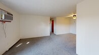 Located at 3120 Staten Ave in Lansing, Michigan, this single-floor, 2-bedroom, 1-bathroom unit offers a practical and functional layout. The combined living room and kitchen area serves as the heart of the space, with the living room featuring gray wall-to-wall carpeting, a wall-mounted air conditioning unit, baseboard heating, and a sliding glass door that opens to a private balcony, allowing natural light to filter in. A ceiling fan is present in the adjoining area near the kitchen entry.

The kitchen is designed with warm wood-toned cabinetry, a peninsula-style counter with a double stainless steel sink, a white electric range, and an overhead exhaust hood, providing efficient use of the available space.

Both bedrooms are carpeted and finished with neutral walls and textured ceilings. The primary bedroom includes a wood-paneled bifold closet and baseboard heating, while the second bedroom features a window with natural light and its own baseboard heater. Each room offers a clean, straightforward layout suitable for standard furnishings.

The bathroom includes tile flooring, a wood-toned vanity with storage, a full tub-shower combination, and a lighted vanity mirror. Throughout the unit, warm wood-toned door trim and consistent neutral tones create a cohesive, understated aesthetic.