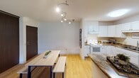 This single-floor residence offers a thoughtfully arranged layout that balances comfort and functionality throughout. The living room serves as a welcoming central space, featuring plush carpeting, neutral walls, and a large sliding glass door that fills the room with natural light and provides access to an outdoor balcony with greenery views. The kitchen is well-equipped with white cabinetry, granite-style countertops, a breakfast bar peninsula, light hardwood-style flooring, and a full suite of appliances including a refrigerator, dishwasher, and range. A track lighting fixture overhead adds a modern touch. Adjacent to the kitchen, a dedicated dining area provides ample space for a full-sized table. The generously sized bedroom features carpet flooring, a wide window allowing natural light, a textured ceiling, and a direct pass-through to one of the bathrooms. A second bedroom offers a clean, open layout with carpet and its own window. Two bathrooms are present — one featuring a tub-shower combination with mosaic tile flooring and a white vanity with storage, and a second half-bath-style space with a matching white vanity. The unit benefits from baseboard heating throughout and dark-accented interior doors that add a contrasting design element.
