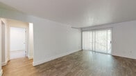 This single-floor residence offers a clean, functional layout with a neutral palette throughout. The spacious living area is finished with wood-style flooring and features a large sliding glass door fitted with vertical blinds, allowing generous natural light and views of surrounding greenery. A front entry door opens directly into this open living space, which flows seamlessly into the rest of the home.

The kitchen is equipped with warm-toned wooden cabinetry, light speckled countertops, a coil-element range with oven, a dishwasher, and a utility sink — providing a practical and well-organized cooking environment. An adjacent secondary room, also with wood-style flooring and a window overlooking the outdoors, offers flexible use as a dining area or additional living space.

The bedrooms are carpeted for comfort and feature windows that bring in natural light. The primary bedroom is notably well-appointed with an extensive wall of louvered bi-fold closet doors, offering generous storage capacity.

The bathroom presents a clean, all-white aesthetic with a full tub and shower combination, white tile surround, and a window for ventilation and natural light. Throughout the space, crisp white walls, consistent trim work, and practical finishes contribute to a bright, move-in ready environment.