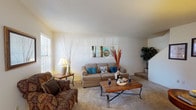 This two-story residence offers a thoughtfully arranged floor plan with two bedrooms and one and a half bathrooms. The main level features a carpeted living room filled with natural light from multiple windows fitted with blinds, creating a bright and welcoming atmosphere. A staircase connects the two floors, visible from the living area. Adjacent to the living room, the dining area benefits from large sliding glass doors dressed with vertical blinds, allowing generous natural light to filter in while providing direct access to the outdoors. The kitchen is efficiently laid out with white cabinetry extending to the ceiling, offering ample storage. It is equipped with a white electric range, a black dishwasher, a double sink, and a refrigerator. A half bathroom on the main level features tile wainscoting, a vanity with a marble-style countertop, and a textured ceiling. Both bedrooms are located on the upper floor, each carpeted and well-proportioned with windows that bring in natural light. The full bathroom upstairs includes a tiled tub-shower combination, a vanity, and a mirror. Throughout the home, neutral tones and textured ceilings maintain a cohesive and understated aesthetic.