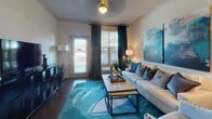 This single-story residence offers a thoughtfully designed layout connecting living, dining, and kitchen spaces in a cohesive open arrangement. The kitchen is equipped with stainless steel appliances, including a French door refrigerator, electric range, and over-the-range microwave. Rich dark cabinetry pairs with granite countertops throughout, and a peninsula with bar seating and pendant lighting serves as both a functional workspace and casual dining area. Hardwood-style flooring extends through the kitchen, dining, and living areas, while crown molding adds a refined architectural detail.

The dining area accommodates a round glass-top table beneath a track lighting fixture, and the living room features a private exterior door, natural light from large windows with blinds, and ample space for full-size furnishings.

Both bedrooms are carpeted and include ceiling fans, multiple windows with natural light, and generous room for bedroom furniture. The primary bedroom features an en-suite bathroom with a double-sink vanity, granite countertops, dark cabinetry, and a shower-tub combination. A second full bathroom mirrors the same cabinetry and countertop finishes, providing a consistent design aesthetic throughout the home.