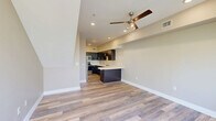 This three-bedroom, two-bathroom multi-story home in Reno, Nevada is spread across three floors, offering a well-organized layout with dedicated spaces for living, sleeping, and utility. The ground floor houses an attached garage with a polished concrete floor, automatic opener, and ample storage space. The main living floor serves as the heart of the home, featuring an open-concept kitchen and living area. The kitchen is appointed with dark espresso cabinetry, white quartz countertops, stainless steel appliances including a range, microwave, and dishwasher, and durable wood-look flooring. Built-in open shelving adds convenient storage adjacent to the kitchen. The living area is bright with natural light streaming through large windows. The upper floor accommodates the three bedrooms and two bathrooms. The bedrooms feature plush carpeting, ceiling fans, and large windows — one offering a view of a neighboring balcony streetscape, while another captures lush tree canopy. The bathrooms are finished with dark vanity cabinetry, light countertops, tile flooring, and sliding glass shower enclosures. A standout feature of the home is the balcony, which frames a stunning view of the Truckee River and surrounding mature trees, providing a serene natural backdrop to this urban Reno residence.