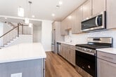 Located at 38 Old Short Hills Rd in Livingston, NJ, this well-appointed two-floor home offers a thoughtfully designed layout with modern finishes throughout. The main living level centers around an open-concept kitchen and living area, where warm hardwood-style flooring flows seamlessly underfoot. The kitchen is equipped with stainless steel appliances, including a gas range, built-in microwave, and French door refrigerator, complemented by gray shaker-style cabinetry, a crisp white subway tile backsplash, and a generous island with pendant lighting above. Large windows and sliding door access bring in abundant natural light and provide outdoor views, enhancing the airy feel of the living space. A convenient half bathroom with a dark wood vanity and wood-look flooring serves the main level. Upstairs, the spacious primary bedroom features plush carpeting and is paired with an expansive walk-in closet outfitted with wire shelving systems. The primary bathroom impresses with a dual-sink vanity topped in white quartz, rich dark wood cabinetry, and large-format tile flooring. Additional walk-in closet space and a dedicated laundry room with a full-size washer and dryer round out the upper level, making this home as functional as it is refined.