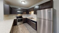 Located at 4601 Ash Grove Dr in Springfield, Illinois, this single-floor residence offers a well-designed layout with modern finishes throughout. The kitchen is a standout feature, showcasing rich dark cabinetry, light stone-look countertops, and a full suite of stainless steel appliances including a range, over-the-range microwave, dishwasher, and refrigerator. Wood-look luxury vinyl plank flooring runs through the kitchen and entry areas, providing durability and a contemporary aesthetic. The open living area transitions seamlessly from the kitchen, combining hard-surface and plush carpeted flooring, and is equipped with a ceiling fan and recessed lighting. Natural light enters through windows that offer views of the surrounding landscape. The bedrooms are generously sized, each featuring soft carpet, ceiling fans, and windows that bring in outdoor views and natural light. Closet access is available in the bedrooms for convenient storage. The bathrooms are clean and functional, offering both a soaking tub with surround and a separate walk-in shower stall with a built-in shelf, complemented by brushed nickel hardware. Neutral gray wall tones are carried throughout the home, creating a cohesive and move-in-ready atmosphere.