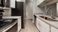 Located at 3939 Waterville Ct in Henrico, Virginia, this single-floor residence offers a clean, modern interior with consistent wood-look flooring throughout. The open living area is anchored by a pass-through kitchen connection and sliding glass door that fills the space with natural light. Vertical blinds provide privacy while maintaining a bright, airy atmosphere.

The galley-style kitchen is well-equipped with white cabinetry, granite-look countertops, stainless steel appliances including a refrigerator, range, and dishwasher, and light-toned flooring that complements the overall design. A textured ceiling adds character throughout the home.

Multiple bedrooms feature dark wood-look flooring, neutral gray walls, and windows overlooking lush greenery, creating a calm and comfortable environment. Each room is thoughtfully designed with ample wall space and closet access.

The bathroom is finished with white cabinetry, a single-sink vanity, brushed nickel hardware, and a tub/shower combination, maintaining the home's cohesive, neutral aesthetic. The layout flows efficiently from room to room, making the space practical and easy to navigate. Overall, the home presents a move-in-ready interior with updated finishes throughout.