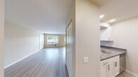 Located at 3030 NE 143rd St. in Seattle, WA, this two-bedroom, one-bathroom unit offers a well-organized, single-floor layout designed for comfortable everyday living. The entrance opens to a bright, open living area featuring light wood-style flooring and neutral warm-toned walls that create a clean, welcoming atmosphere. Large windows allow natural light to flow throughout, providing views of the surrounding neighborhood.

The galley-style kitchen is efficiently designed with white shaker cabinetry, gray countertops, a stainless steel sink, a dishwasher, and an electric range, maximizing both storage and workspace within a compact footprint.

The generously sized primary bedroom is carpeted and features sliding glass doors that open directly onto a private balcony, offering outdoor access and additional natural light. The second bedroom also features light wood-style flooring and connects conveniently to the shared bathroom area.

The bathroom includes a wide vanity with white cabinetry, gray countertops, an oversized mirror, and well-placed overhead lighting. A dedicated walk-in closet with built-in shelving provides ample storage. Throughout the unit, the neutral color palette, clean finishes, and thoughtful layout come together to create a practical and comfortable living space.