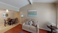 This single-floor residence offers a thoughtfully arranged layout that balances comfort and functionality throughout its main living areas. The living room serves as the heart of the home, showcasing vaulted ceilings with an exposed beam accent and rich hardwood flooring. Natural light streams through a large sliding glass door, brightening the space and creating an inviting atmosphere. Crown molding adds a refined architectural detail throughout the main areas.

Adjacent to the living room, the dining area features tile flooring and accommodates a round dining table with ample seating, making it well-suited for gatherings. The kitchen is equipped with white cabinetry, an electric range, and a built-in pantry closet, offering practical storage and workspace.

The primary bedroom is carpeted and finished with crown molding and a ceiling fan, providing a calm retreat with natural light from a window. It connects directly to a full bathroom, adding a convenient en-suite feel. A second bedroom mirrors the comfortable design with similar finishes and ceiling fan. The bathroom features a tiled tub-and-shower combination with clean, neutral tones.

Throughout the home, warm beige walls and consistent trim work create a cohesive, neutral palette that feels both welcoming and easy to personalize.