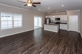 Located at 2209 Ashford Villa Circle in Chattanooga, TN, this single-floor home offers a well-designed, open-concept layout that seamlessly connects the living and kitchen areas. Rich, dark hardwood-style flooring flows throughout the space, complemented by neutral-toned walls and crisp white trim that create a clean, cohesive aesthetic.

The kitchen is a standout feature, showcasing white shaker-style cabinetry, granite countertops with subtle veining, a white subway tile backsplash, and a full suite of stainless steel appliances including a refrigerator, range, and microwave. A center island with an integrated sink and pendant lighting above adds both function and style, while a sliding glass door brings in abundant natural light and provides outdoor access.

The living area is generously proportioned, featuring crown molding, recessed lighting, and a ceiling fan — creating a comfortable, airy atmosphere. Bedrooms continue the hardwood-style flooring and include ceiling fans and open closets with built-in shelving for practical storage.

The bathroom is well-appointed with white cabinetry, granite countertops, a single undermount sink, a large mirror, and a tub/shower combination. A window allows natural light to brighten the space. Hallways feature additional closet storage, rounding out this thoughtfully laid-out home.