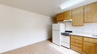 Located at 9703 Winter Gardens Boulevard in Lakeside, CA, this one-bedroom, one-bathroom unit offers a practical and efficient single-floor layout. The open living and kitchen area transitions seamlessly between carpeted flooring and tiled surfaces, creating a clear distinction between functional zones. The kitchen is equipped with warm oak-toned cabinetry, a white range, a full-size refrigerator, and an L-shaped countertop with a built-in sink. A window with vertical blinds allows natural light into the kitchen and dining area, while a wall-mounted AC unit provides climate control. The living area is carpeted and opens directly from the kitchen, offering a simple, easy-to-furnish space. The bedroom is generously sized relative to the overall footprint, featuring soft carpeting, a ceiling fan with light fixture, a window overlooking the exterior, and a sliding-door closet with a full-width hanging rod for storage. The bathroom is clean and functional, featuring tile flooring, a tub and shower combination with a handheld showerhead, a toilet, and a vanity with an oak cabinet base and mirrored medicine cabinet above. This unit provides a straightforward, low-maintenance living space in a residential Lakeside neighborhood.