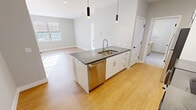 This contemporary 610 square foot apartment offers a thoughtful blend of style and functionality. The open-concept design seamlessly integrates the kitchen, living, and dining areas, creating a spacious feel within the compact layout. The kitchen is a standout feature, boasting crisp white cabinetry, stainless steel appliances, and a stylish subway tile backsplash. A central island with a built-in sink and ample counter space serves as both a practical workspace and a casual dining area.

The 140 square foot bedroom provides a cozy retreat, complete with large windows that flood the space with natural light. The bathroom is well-appointed with modern fixtures, including a vanity with a marble-like countertop and a shower/tub combination. Throughout the apartment, warm wood-tone flooring contrasts beautifully with the neutral wall colors, creating a welcoming ambiance.

Attention to detail is evident in the lighting choices, with a mix of recessed lights and pendant fixtures adding both functionality and aesthetic appeal. The apartment's single floor layout and clever use of space make it an ideal choice for those seeking a low-maintenance yet stylish urban dwelling.