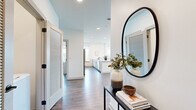 Located in Nashville's vibrant 37204 corridor, this 3-bedroom, 2-bathroom residence offers a thoughtfully designed single-floor layout with clean, contemporary architecture and an abundance of natural light. Warm hardwood-style flooring flows throughout, tying together the open-concept living, dining, and kitchen areas. The kitchen is a standout feature, outfitted with light sage cabinetry, quartz countertops, stainless steel appliances, a subway tile backsplash, and a large island with bar seating — ideal for entertaining. A tall window frames city views from the kitchen, while expansive floor-to-ceiling windows in the dining area flood the space with daylight and offer sweeping urban panoramas. The living room is bright and inviting, with direct access to a private balcony featuring a wood-paneled ceiling. The primary bedroom is generously sized, with large windows overlooking the Nashville skyline, a ceiling fan, and access to a spacious walk-in closet with built-in wire shelving. Additional bedrooms are well-proportioned with ample natural light. The bathrooms are finished with stone-look tile flooring, quartz vanities, and a clean white tiled tub-shower. A welcoming entryway with louvered doors completes this polished, move-in-ready home.