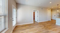 Located at 215 E Lincolnway in Valparaiso, Indiana, this well-appointed one-bedroom, one-bathroom unit offers a thoughtfully designed open-concept layout finished with light wood-tone luxury vinyl plank flooring throughout. The kitchen serves as the heart of the space, showcasing white shaker cabinetry with matte black hardware, granite countertops, a classic subway tile backsplash, stainless steel appliances including a dishwasher and refrigerator, and a central island topped with pendant lighting — ideal for both cooking and casual dining. The kitchen flows seamlessly into a combined dining and living area, which benefits from natural light through large windows overlooking the surrounding neighborhood. A dedicated pantry provides additional storage convenience. The spacious bedroom features generous windows that fill the room with natural light and connects to a dedicated laundry room outfitted with a stacked washer and dryer. The full bathroom is finished with granite counters, white subway tile in the walk-in shower with a black-framed glass door, and coordinating matte black fixtures. A private balcony extends the living space outdoors, while a utility room rounds out the functional layout of this modern Valparaiso residence.