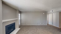 This well-appointed single-floor, one-bedroom, one-bathroom unit offers a functional and comfortable layout across a compact yet efficient footprint. The living room serves as the centerpiece of the space, featuring plush carpeting, a textured ceiling, and a tile-surround fireplace flanked by two windows that allow natural light to fill the room. A ceiling fan adds both style and practicality near the entryway. Neutral gray walls and clean white trim create a cohesive, modern aesthetic throughout. The kitchen is equipped with stainless steel appliances, including a full-size refrigerator and range, complemented by gray cabinetry, a decorative mosaic tile backsplash, and light countertops. Wood-look flooring grounds the kitchen and connects it to the hallway. The bedroom offers carpeted flooring, soft gray walls, and access to a dedicated walk-in closet with built-in shelving for ample storage. The bathroom features gray cabinetry with a white quartz-style countertop, a framed mirror, modern light fixtures, and wood-look flooring. A dedicated in-unit laundry area houses a full-size washer and dryer with overhead shelving, adding significant everyday convenience to this thoughtfully designed home.