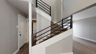 Located in Dallas, TX 75219, this two-story residence offers a well-designed layout spread across two levels. The main floor features durable wood-look flooring throughout the open living and dining areas, anchored by a contemporary chandelier that adds a refined touch. A carpeted staircase with sleek black metal railings connects both floors, serving as a stylish architectural focal point.

The kitchen is efficiently laid out with white cabinetry, dark granite-look countertops, and black appliances including a range, refrigerator, and dishwasher, complemented by a tile backsplash and a window that brings in natural light.

The bedrooms are carpeted for comfort and each features a ceiling fan, natural light from windows with blinds, and generous closet space — including dual closets in one bedroom. One bedroom includes direct access to an en-suite bathroom.

The bathrooms are updated with white cabinetry, dark granite countertops, black hardware accents, framed mirrors, and tiled tub-shower combinations with wood-look flooring. The consistent use of neutral gray tones throughout the space creates a clean, cohesive aesthetic that is both modern and inviting.