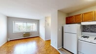 Located at 40 Zabriskie St in Hackensack, New Jersey, this efficiently designed single-floor unit offers a well-organized layout comprising a combined living and kitchen area along with a full bathroom. The living space is highlighted by classic parquet hardwood flooring that adds warmth and character throughout. A wide sliding window floods the room with natural light while offering views of the surrounding Hackensack neighborhood, and a wall-mounted air conditioning unit and baseboard heating ensure year-round comfort. The kitchen is equipped with warm-toned wooden cabinetry, a mosaic tile backsplash, dark countertops, and white appliances, creating a functional and inviting cooking space. The open entry area flows naturally into the kitchen, providing a practical and welcoming transition into the unit. The bathroom is thoughtfully appointed with cool-toned vinyl plank flooring, marble-styled shower surround, a standard tub and shower combination, a toilet, and a small window that allows in natural light. Neutral gray wall tones throughout the unit lend a clean, contemporary feel. White trim and baseboards provide crisp definition to each space, contributing to the overall bright and tidy aesthetic of this compact but complete Hackensack residence.