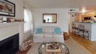 This single-floor apartment at Rosemeade Apartments in Southbridge, Massachusetts offers a well-designed layout with 2 bedrooms and 2 bathrooms. The living room serves as a central gathering space, highlighted by a classic wood-burning fireplace flanked by two windows that allow generous natural light to fill the room. Neutral-toned carpet and light walls create a clean, inviting atmosphere throughout.

The adjacent dining area transitions seamlessly from the living space onto wood-style flooring, with a sliding glass door providing access to the exterior. The kitchen features light wood cabinetry, a granite-style countertop with a breakfast bar, stainless steel appliances—including a range and refrigerator—and matching wood-style flooring, offering a functional and cohesive design.

Both bedrooms are carpeted and comfortably sized, each equipped with ceiling fans and windows for natural light. The primary bedroom includes an en-suite bathroom with a single-sink vanity, warm wood cabinetry, and wood-style flooring. A second full bathroom, accessible from the hallway, mirrors this design with a shower/tub combination and matching finishes. The overall aesthetic throughout the space is consistent, clean, and practical.