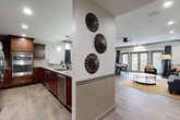 Located at 4900 S Cobb Drive SE in Smyrna, Georgia, this single-story club room offers a thoughtfully designed communal space combining functionality with refined aesthetics. Wood-look tile flooring flows seamlessly throughout, anchoring the warm, cohesive design.

The fully equipped kitchen is a standout feature, showcasing rich dark-stained cabinetry, granite countertops with a subway tile backsplash, stainless steel appliances including a French door refrigerator, double wall ovens, and a dishwasher. Pendant lighting illuminates the counter seating area, making it well-suited for casual gatherings or catered events.

The open lounge area features a comfortable seating arrangement centered around a marble-top coffee table and an ornate area rug. A large framed landscape painting anchors the wall, and French doors with arched transom windows invite natural light while providing outdoor access.

A dedicated dining area accommodates a large round table with upholstered seating, while a separate meeting or private dining room features a wall-mounted flat-screen TV, a farmhouse-style dining table, upholstered chairs, and elegant drapery. Crown molding and chair-rail detailing add architectural polish throughout the entire space.