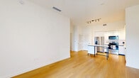 Located in Miami Lakes, this thoughtfully designed two-bedroom, one-bathroom residence offers a clean, modern aesthetic throughout. Light wood flooring runs continuously across the entire unit, creating a warm and cohesive feel from room to room. The open-concept living and kitchen area serves as the heart of the home, where the sleek kitchen stands out with white flat-panel cabinetry extending to the ceiling, stainless steel appliances including a refrigerator with ice maker, electric range, microwave, and dishwasher, all complemented by a white countertop and classic subway tile backsplash. A kitchen island with a contrasting dark frame adds a modern design touch. Track lighting illuminates the space effectively. The living area flows naturally from the kitchen, offering a bright, open environment. Both bedrooms are well-proportioned and finished in crisp white tones. The primary bedroom features direct access to a private outdoor balcony with views of surrounding greenery and a ceiling fan for added comfort. The second bedroom benefits from a large window framing tropical outdoor views. A spacious walk-in closet with built-in wire shelving provides generous storage. The bathroom is finished with a white vanity, large-format tiled walk-in shower with sliding glass doors, and wood-tone flooring, maintaining the unit's clean, contemporary style throughout.