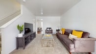 This multi-floor residence at Arbor Homes offers a well-organized layout across three floors, providing distinct living zones for comfort and functionality. The living room serves as the central gathering space, featuring neutral-toned wall-to-wall carpeting, clean white walls, and a vaulted ceiling that lends an open, airy feel. A front-facing window allows natural light to fill the room, creating a bright and welcoming atmosphere. The space flows naturally toward a dedicated dining area, visible through an open passageway.

The kitchen is equipped with stainless steel appliances, including a gas range and full-sized refrigerator, complemented by warm oak-toned cabinetry offering ample storage. Light-colored countertops and durable hardwood-style flooring complete the practical, efficient design.

Both bedrooms are carpeted and bathed in natural light from well-positioned windows. Each room offers a comfortable, restful environment with neutral walls and sufficient space for standard bedroom furnishings.

The full bathroom features hardwood-style flooring, a combined tub and shower with a curved curtain rod, and a wooden vanity with under-sink storage, maintaining a clean and classic aesthetic throughout.