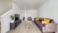 This multi-floor residence at Arbor Homes offers a well-organized layout across three floors, providing distinct living zones for comfort and functionality. The living room serves as the central gathering space, featuring neutral-toned wall-to-wall carpeting, clean white walls, and a vaulted ceiling that lends an open, airy feel. A front-facing window allows natural light to fill the room, creating a bright and welcoming atmosphere. The space flows naturally toward a dedicated dining area, visible through an open passageway.

The kitchen is equipped with stainless steel appliances, including a gas range and full-sized refrigerator, complemented by warm oak-toned cabinetry offering ample storage. Light-colored countertops and durable hardwood-style flooring complete the practical, efficient design.

Both bedrooms are carpeted and bathed in natural light from well-positioned windows. Each room offers a comfortable, restful environment with neutral walls and sufficient space for standard bedroom furnishings.

The full bathroom features hardwood-style flooring, a combined tub and shower with a curved curtain rod, and a wooden vanity with under-sink storage, maintaining a clean and classic aesthetic throughout.