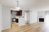 Located at 14955 Saticoy St in Los Angeles, CA, this 2-bedroom, 1-bathroom unit offers a thoughtfully designed single-floor layout that maximizes functionality and comfort. Light wood-tone flooring runs throughout, complementing the neutral gray walls and textured ceilings to create a bright, cohesive aesthetic.

The open-concept kitchen and living area serves as the heart of the home. The kitchen features rich dark espresso cabinetry, stainless steel appliances including a refrigerator, microwave, and range, and a peninsula with a white countertop accented by a stylish pendant light. The living area is highlighted by a classic white-mantled fireplace and access to an exterior door, filling the space with natural light.

Both bedrooms are well-sized, with large windows fitted with vertical blinds that allow ample natural light to filter through. The primary bedroom includes mirrored sliding closet doors that open to a built-in shelving system, offering generous storage. The second bedroom is equally bright and open.

The bathroom is clean and modern, featuring dark wood cabinetry with a white countertop vanity, a framed mirror, brushed nickel fixtures, and a full tub-shower combination with a skylight above for added brightness. The overall design is clean, updated, and move-in ready.