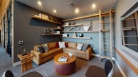 Located at 11108 Chandler Blvd in Los Angeles, this single-story amenity space blends modern design with warm, inviting materials throughout its distinct functional areas. The open coworking hub serves as a central gathering point, featuring a substantial marble-topped wood island illuminated by an industrial-style pendant cluster with Edison bulbs. Built-in wood shelving with curated décor lines the walls, and steel-framed glass partitions define the space while maintaining visual connectivity and an abundance of natural light.

The conference room is a standout feature, distinguished by a richly textured mosaic accent wall composed of varied tile artwork, creating a unique and creative backdrop. A dark wood conference table is surrounded by chevron-stitched leather chairs, while a bold multi-pendant black and brass chandelier adds sophistication overhead. A large flat-screen display is integrated into a wood and white brick media wall.

The lounge area offers a relaxed, residential feel with a generous sectional sofa in warm gold tones, a round drum coffee table, and floor-to-ceiling floating shelves styled with decorative objects. Together, these spaces create a cohesive, design-forward environment ideal for collaboration and community.