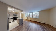 This well-appointed 2-bedroom, 1-bathroom unit is laid out on a single floor, offering a functional and comfortable living space. The open-concept kitchen and living room form the heart of the unit, where rich hardwood-style flooring extends throughout and a wall of large windows floods the area with natural light while framing views of the surrounding urban streetscape. A ceiling fan adds a practical touch to the living area.

The kitchen is thoughtfully designed with contemporary grey cabinetry, granite-look countertops, a tile backsplash with a decorative mosaic accent strip, and a full suite of stainless steel appliances including a refrigerator, stove, and over-the-range microwave. A peninsula with a matching countertop provides additional workspace and a natural division between the kitchen and living areas. The kitchen is finished with light tile flooring and track lighting overhead.

Both bedrooms feature the same warm hardwood-style flooring and are equipped with mirrored sliding closet doors, maximizing both storage and the sense of space. The primary bedroom benefits from a generous footprint and a large window with a city view. The bathroom is finished with full-height cream ceramic wall tiles, a decorative mosaic border, and a soaking tub with shower. A hallway connects the rooms, and the entryway provides a defined arrival point into the unit.