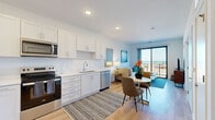 Located at 233 Lake Ave in Racine, Wisconsin, this thoughtfully designed one-bedroom, one-bathroom residence offers a bright, open-concept layout with high-end finishes throughout. Light hardwood flooring flows seamlessly through the main living areas, complementing the clean, contemporary aesthetic.

The kitchen is a standout feature, outfitted with crisp white shaker cabinetry extending to the ceiling, stainless steel appliances including a range, microwave, dishwasher, and refrigerator, and a sleek white countertop with an undermount sink. The kitchen opens directly into the dining and living areas, creating an effortless flow ideal for both daily living and entertaining.

The living room is bathed in natural light courtesy of a floor-to-ceiling sliding glass door that leads to a private balcony, offering impressive views of Lake Michigan and the surrounding cityscape. The bedroom features plush carpeting, a ceiling fan, and large windows that frame stunning lake views, providing a serene retreat. A dedicated closet adds practical storage.

The bathroom is finished in a clean, modern style with a white vanity, mirror, wood-look flooring, and a walk-in shower. Every room reflects a cohesive, contemporary design with a bright, airy ambiance throughout.