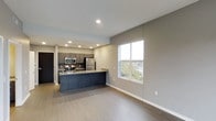 This well-appointed 1-bedroom, 1-bathroom residence offers a thoughtfully designed single-floor layout that maximizes comfort and functionality. The open-concept living and kitchen area creates a seamless flow, anchored by a sleek kitchen island with a dark finish that serves as both a prep space and casual dining spot. The kitchen is equipped with stainless steel appliances, including a refrigerator, microwave, and range, complemented by dark cabinetry that adds a modern, sophisticated touch. Recessed lighting throughout the ceiling provides consistent, well-distributed illumination across the living space. Light wood-tone flooring runs throughout, lending warmth and continuity to the interior. Neutral gray walls provide a clean, versatile backdrop that suits a variety of décor styles. A large window in the living area floods the space with natural light and offers views of the surrounding greenery, enhancing the open and airy feel of the home. The overall ambiance is contemporary and move-in ready, combining practical design with clean aesthetics for comfortable everyday living.