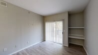 Located at 3653 Timberglen Rd in Dallas, Texas, this two-bedroom, one-bathroom residence offers a practical and well-organized single-floor layout. The living area features wood-look flooring in a warm tone and is anchored by a sliding glass door fitted with vertical blinds, allowing natural light to filter in while providing access to the outdoors. A set of built-in shelves adds functional storage and character to the living space.

The primary bedroom is a comfortable, well-proportioned room carpeted in neutral tones, illuminated by a ceiling fan light fixture, and brightened by two windows with outdoor views. It provides access to a spacious walk-in closet outfitted with wire shelving on three walls, offering generous storage capacity. The second bedroom also features wood-look flooring and benefits from natural light.

The bathroom is clean and straightforward, featuring a full tub-shower combo with white tile surround, alongside standard fixtures. A dedicated utility room rounds out the floor plan, adding everyday convenience.

Throughout the home, neutral gray walls, white trim, and consistent flooring choices create a cohesive, move-in-ready aesthetic. The overall layout is efficient and functional, making excellent use of the available space.