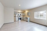 Located at 5440 Steilacoom Blvd SW in Lakewood, Washington, this single-floor, one-bedroom, two-bathroom unit offers a well-organized and efficiently designed layout. The open-concept main living area seamlessly combines the living room, dining space, and kitchen into one bright, cohesive area. Light wood-style flooring runs throughout, complementing the neutral warm-beige walls and clean white ceilings with recessed lighting.

The kitchen is outfitted with grey shaker-style cabinetry, white countertops, and a full suite of stainless steel appliances including a refrigerator, range, microwave, and dishwasher. A window over the kitchen area allows natural light to fill the space. The living area also features a large sliding glass door with vertical blinds, providing additional natural light and outdoor views.

The bedroom is a comfortable, private retreat featuring light wood-style flooring, neutral walls, and access to a dedicated closet with built-in shelving. The unit includes two full bathrooms, one of which features a vanity with grey cabinetry, white countertop, and a tub-shower combination. A hallway connects the main living areas to the bedroom and bathrooms, with three closets total providing generous storage throughout the unit.