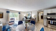 This single-floor, 2-bedroom, 2-bathroom residence offers a thoughtfully designed layout that balances comfort and functionality. The open living and dining area features wood-look flooring, neutral tones, and a bold navy accent wall that anchors the living space, creating a modern and inviting atmosphere. A glass-top dining table and a dedicated workspace with ample natural light from a large sliding glass door add versatility to the main living area.

The kitchen is well-equipped with white shaker cabinetry, granite-style countertops, stainless steel appliances including a range, microwave, and dishwasher, and a window above the sink that lets in natural light. It offers generous counter and storage space for everyday use.

Both bedrooms are carpeted and filled with natural light from large windows with stylish drapery. The primary bedroom features a ceiling fan and ample space, while the second bedroom offers a bright, serene retreat. Each room carries a cohesive color palette of blues and grays that flows throughout the home.

The bathrooms are finished with granite-topped vanities and white cabinetry, complemented by natural light from frosted windows. Overall, the residence presents a clean, contemporary aesthetic with a warm and livable ambiance throughout.