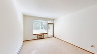 Located in Spokane, WA, this 2-bedroom, 1-bathroom unit offers a well-organized, single-floor layout designed for comfortable everyday living. The living area features neutral-toned carpet, warm wood baseboards, and access to a private balcony through a glass door, with large windows that bring in generous natural light and outdoor views of surrounding greenery. The kitchen is equipped with warm wood cabinetry, a tile backsplash, laminate flooring, an electric range, built-in microwave, refrigerator, and a breakfast bar peninsula that opens to the main living space. Both bedrooms are carpeted and naturally lit, with the primary bedroom offering a comfortable footprint, and the second bedroom featuring a sliding door closet for ample storage. A dedicated hallway connects the rooms, adding to the functional flow of the unit. The bathroom includes a full tub-shower combination, a vanity with a large mirror, and tile countertops. Additional conveniences include two closets, a laundry area, and a utility room. Textured ceilings and consistent warm-toned trim throughout give the unit a cohesive, understated aesthetic well-suited for practical, everyday use.