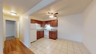 Located at 6000 Jaycox Rd in North Ridgeville, Ohio, this single-floor unit offers a practical and comfortable layout designed for everyday living. The kitchen is equipped with rich, warm-toned cabinetry, granite-style countertops, a double-basin stainless steel sink, a white electric range, and a full-size refrigerator. Light ceramic tile flooring runs throughout the kitchen, providing a clean and durable surface. A ceiling fan with integrated lighting is positioned above the kitchen and adjacent living area, promoting airflow and illumination throughout the open-concept space. The living area transitions seamlessly from the kitchen and features attractive hardwood-style flooring that adds warmth to the interior. A generously sized window in the main room allows natural light to fill the space while offering views of the surrounding neighborhood. A wall-mounted air conditioning unit and baseboard heating ensure year-round climate comfort. The bathroom is well-appointed with a full tub and shower combination, a wood-toned vanity with a white basin, a medicine cabinet with a mirrored door, and neutral tile flooring. The overall aesthetic of the unit is clean and understated, with neutral wall tones and straightforward finishes that create a welcoming, move-in-ready environment.
