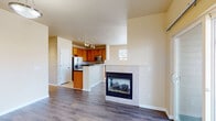 Located at 7020 Simms St in Arvada, Colorado, this single-floor residence offers a well-designed open-concept layout that connects the living area and kitchen seamlessly. The living space features warm hardwood-style flooring and a tile-surround fireplace, creating a welcoming focal point. The kitchen is equipped with rich wood cabinetry, dark granite countertops, stainless steel appliances including a refrigerator, microwave, and range, and a peninsula that provides additional counter space and casual seating. Track lighting illuminates both the kitchen and living area efficiently. A window in the kitchen allows natural light to brighten the space. The bedrooms offer plush carpeting, neutral wall tones, and ample room for furnishings. One bedroom includes direct access to a closet and adjoining bathroom. The bathroom is finished with tile flooring, a dual-sink vanity featuring dark granite countertops and warm wood cabinetry, and a full tub and shower with tile surround. A dedicated laundry room houses a full-size washer and dryer. The overall aesthetic is consistent throughout, with warm neutral tones and functional finishes that contribute to a comfortable, cohesive living environment.