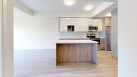 Located at 49 Walnut in Hamilton, Ontario, this thoughtfully designed one-bedroom, one-bathroom unit offers a contemporary living experience across a single floor. Light-toned laminate flooring flows consistently throughout the space, enhancing its bright, cohesive feel.

The kitchen is a standout feature, designed in an open-concept layout with a central island finished in warm wood tones and a crisp white countertop. Upper cabinetry combines high-gloss white panels with wood-accented lower cabinets, complemented by a full suite of stainless steel appliances including a range, microwave, dishwasher, and refrigerator. A tile backsplash adds a clean, polished finish.

The kitchen opens directly into the living area, creating an efficient and sociable layout well-suited for everyday living. The bedroom is a well-proportioned retreat featuring a dramatic floor-to-ceiling window that frames expansive views of the Hamilton city skyline, flooding the room with natural light.

The bathroom is finished in a clean, minimalist style with a full soaker tub and shower combination, white tile surround, and brushed nickel fixtures, maintaining the modern aesthetic found throughout the unit.

Overall, the space presents a clean, contemporary design with neutral tones, quality finishes, and functional layout — ideal for urban living in the heart of Hamilton.