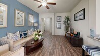 Located at 21 Gramercy Park Dr in Bryan, TX, this single-story 2-bedroom, 2-bathroom home offers a thoughtfully designed layout across a comfortable footprint. The open living area features wood-look flooring, vaulted ceilings with a ceiling fan, and a striking blue accent wall that adds character to the space. Large windows allow ample natural light throughout. The living area flows seamlessly into the dining space, which is brightened by multiple windows dressed with decorative curtains and plantation shutters.

The kitchen is well-equipped with rich dark cabinetry, granite-look countertops, stainless steel appliances including a range and over-the-range microwave, and matching wood-look flooring. The spacious primary bedroom features plush carpet, a ceiling fan, and generous room for a dedicated workspace. The second bedroom is equally comfortable with carpet flooring and natural light. Both bathrooms include dark wood vanity cabinetry with stone countertops and wood-look tile flooring; one bath features a full tub-shower combination. A dedicated laundry room accommodates a full-size washer and dryer with built-in shelving for storage.