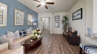 Located at 21 Gramercy Park Dr in Bryan, TX, this single-story 2-bedroom, 2-bathroom home offers a thoughtfully designed layout across a comfortable footprint. The open living area features wood-look flooring, vaulted ceilings with a ceiling fan, and a striking blue accent wall that adds character to the space. Large windows allow ample natural light throughout. The living area flows seamlessly into the dining space, which is brightened by multiple windows dressed with decorative curtains and plantation shutters.

The kitchen is well-equipped with rich dark cabinetry, granite-look countertops, stainless steel appliances including a range and over-the-range microwave, and matching wood-look flooring. The spacious primary bedroom features plush carpet, a ceiling fan, and generous room for a dedicated workspace. The second bedroom is equally comfortable with carpet flooring and natural light. Both bathrooms include dark wood vanity cabinetry with stone countertops and wood-look tile flooring; one bath features a full tub-shower combination. A dedicated laundry room accommodates a full-size washer and dryer with built-in shelving for storage.