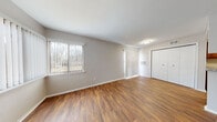 Located at 5902 Boulder Creek Ct in Hazelwood, Missouri, this two-floor residence offers a well-organized layout with practical finishes throughout. The main living area features rich wood-look laminate flooring, neutral gray walls, and a large window fitted with vertical blinds that invite natural light while providing an outdoor view of surrounding trees. A closet and built-in vent add to the room's functionality.

The kitchen is designed for efficiency, featuring warm honey-toned cabinetry that extends to the upper walls, offering generous storage space. Light granite-style countertops complement the stainless steel double sink, while white appliances including a refrigerator and electric range complete the space. Wood-look flooring continues throughout the kitchen for a cohesive look.

The bathroom is appointed with a matching wood-toned vanity, granite-style countertop, a full-width mirror, and brushed nickel fixtures. A shower-tub combination and adjacent toilet round out the well-appointed space.

Carpeted bedrooms provide a softer, quieter environment. One room features a lofted or raised platform element, adding an architectural detail of interest. Windows with vertical blinds appear throughout, maintaining a consistent, light-filled ambiance across the upper level. The overall palette of neutral tones and warm wood finishes gives the residence a clean, welcoming character.
