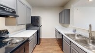 Located at 1810 Graybrook Ln in New Albany, Indiana, this single-floor residence offers a practical and well-organized layout across two bedrooms and three bathrooms. The interior is finished with a neutral color palette of soft whites and warm beiges throughout, creating a clean and cohesive aesthetic.

The galley-style kitchen is a functional highlight, featuring gray shaker-style cabinetry, light marbled countertops, and wood-look flooring. Black appliances, including a coil-burner electric range, refrigerator, and dishwasher, are integrated into the layout, with ample upper and lower cabinet storage lining both walls.

Both bedrooms are carpeted and receive natural light through windows with views of the surrounding greenery. The primary bedroom includes a wall sconce and access to a closet, while the second bedroom offers a similarly bright, open feel with natural sunlight filtering through blinds.

The three bathrooms maintain a consistent design language, featuring gray vanity cabinetry with light countertops, wood-look flooring, and bright vanity lighting. At least one bathroom includes a full tub-shower combination with a curved curtain rod and grab bar. The overall ambiance of the residence is clean, understated, and move-in ready.