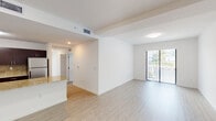 Located at 13735 SW 262nd St in Homestead, Florida, this single-floor, 3-room unit offers a clean, modern design throughout. The open living area is finished with light wood-style flooring and crisp white walls, creating a bright and airy atmosphere. Structural ceiling beams add a subtle architectural detail to the space. A sliding glass door connects the living area to an outdoor balcony, allowing natural light to flow in and providing views of the surrounding greenery.

The kitchen is outfitted with dark flat-panel cabinetry, granite countertops with a matching backsplash, and stainless steel appliances including an electric range and over-the-range microwave — offering a contemporary and functional cooking space.

The bedroom features the same light wood-style flooring, a closet with built-in shelving, and its own sliding glass door with transom window above, filling the room with natural light and providing direct outdoor access.

The bathroom is finished with large-format neutral tile lining the walls of a full tub-shower combination, maintaining the unit's clean, understated aesthetic. Throughout the space, the consistent use of neutral tones and modern finishes creates a cohesive and inviting environment.