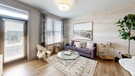 Located on Central Avenue in Charlotte's vibrant Plaza Midwood neighborhood, this well-appointed one-bedroom, one-bathroom residence offers a thoughtfully designed open-concept layout across a single floor. Wide-plank hardwood-style flooring flows seamlessly through the living, dining, and kitchen areas, creating a cohesive and airy feel. The living room is bathed in natural light from large windows dressed with horizontal blinds and patterned drapes, complementing the neutral palette of the walls and ceiling. The kitchen is outfitted with warm wood cabinetry, a subtle tile backsplash, stainless steel appliances including a French door refrigerator, and track lighting overhead. A dedicated dining area sits adjacent to the kitchen, ideal for everyday meals. The spacious bedroom features plush carpet, a ceiling fan, and oversized windows that invite generous daylight and outdoor views. The bathroom includes a wood-toned vanity with granite countertop, a tub-shower combination, and direct access to a well-organized walk-in closet with wire shelving. A hallway connects all areas of the home efficiently, and the overall design balances modern aesthetics with functional comfort.