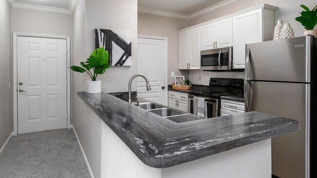 Prepare sus comidas favoritas en esta elegante cocina, que cuenta con electrodomésticos de acero inoxidable, modernos gabinetes blancos y una práctica barra de desayuno perfecta para cenas informales. - Elevate 155