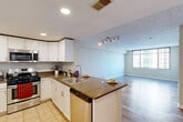 Located at 8200 Dixon Ave in Silver Spring, MD, this well-appointed one-bedroom, one-bathroom residence offers a thoughtfully designed layout across a single floor. The entrance opens into a combined dining and living area bathed in natural light from large floor-to-ceiling windows that frame views of the surrounding Silver Spring skyline. Durable wood-style flooring flows throughout the main living spaces, adding warmth and continuity.

The kitchen is a standout feature, showcasing white cabinetry, dark granite countertops, and a full suite of stainless steel appliances including a gas range, microwave, dishwasher, and refrigerator. A peninsula with an integrated sink and breakfast bar connects the kitchen to the living area, creating an open and functional flow ideal for everyday living and entertaining.

The generously sized bedroom is carpeted for comfort and features large windows that fill the room with natural light and offer elevated views of the city. A dedicated closet provides convenient storage, and the unit includes five closets in total throughout the space.

The bathroom is clean and functional, featuring white cabinetry with granite countertops, a single vanity sink, and a full tub-shower combination with tile surround and light tile flooring. Recessed lighting and a textured ceiling finish are consistent throughout the unit.